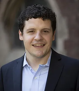 Postdoctoral fellow Luke Mayville wearing light blue shirt and dark blue blazer