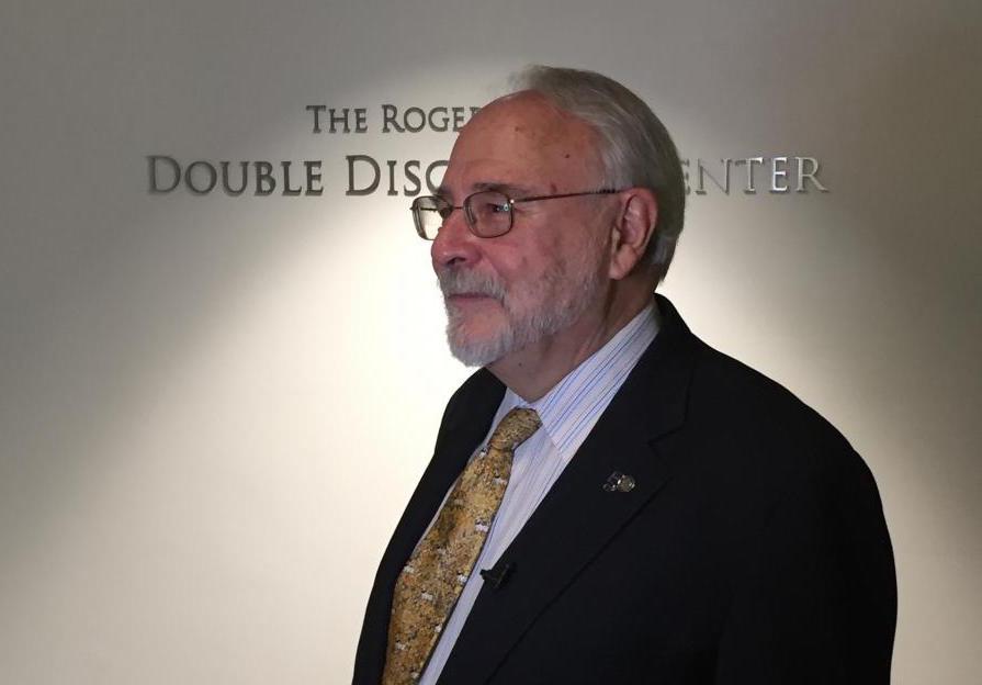 Roger Lehecka stands in front of the nameplate bearing the new name of the Roger Lehecka Double Discovery Center