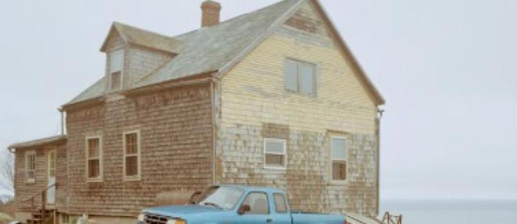Walter Benn Michaels's photograph of clapboard house on the water's edge with light blue pickup truck in foreground